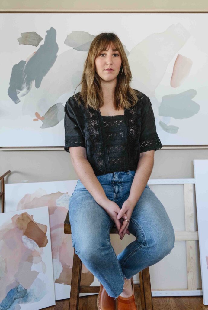 woman sitting a stool in an art studio with a dark contrasting personal branding photoshoot outfit